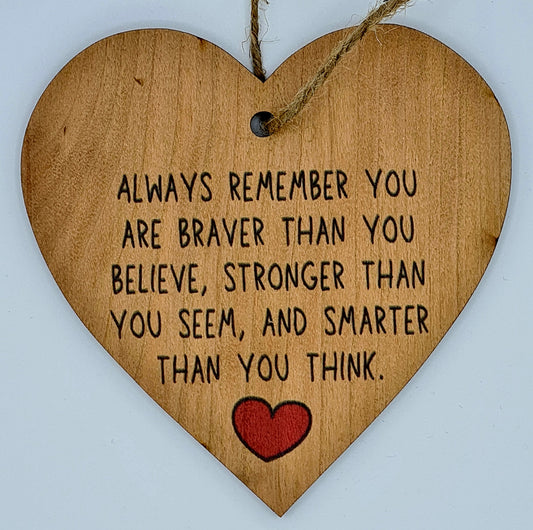 Heart shaped wooden plaque with the slogan "Always Remember you are braver than you believe, stronger than you seem, and smarter than you think". There is a little red heart underneath the writing and a jute string at the top for hanging.