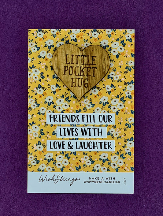 Heart shaped wooden token with the wording "Little Pocket Hug" mounted on yellow card with flowers and the message "Friends fill our lives with love & laughter". 