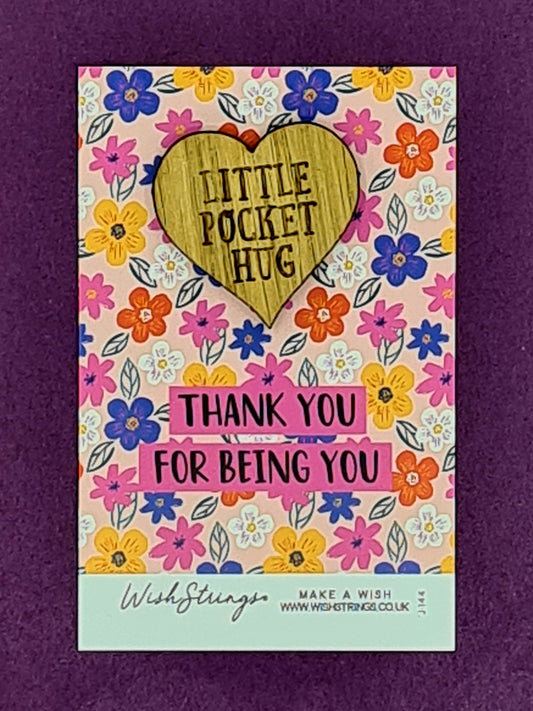 Small wooden heart shaped token saying "Little Pocket Hug". It is mounted on card with lots of different coloured flowers and the message "Thank You for Being You". 