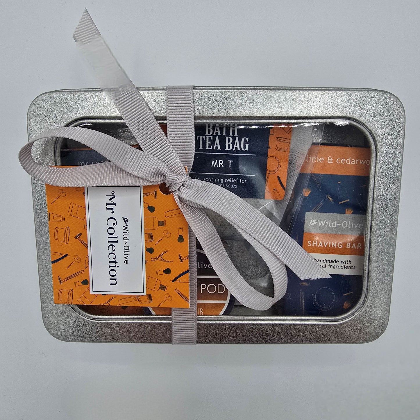 Silver gift tin containing bath, shower and shaving products from Wild Olive Mr Collection.